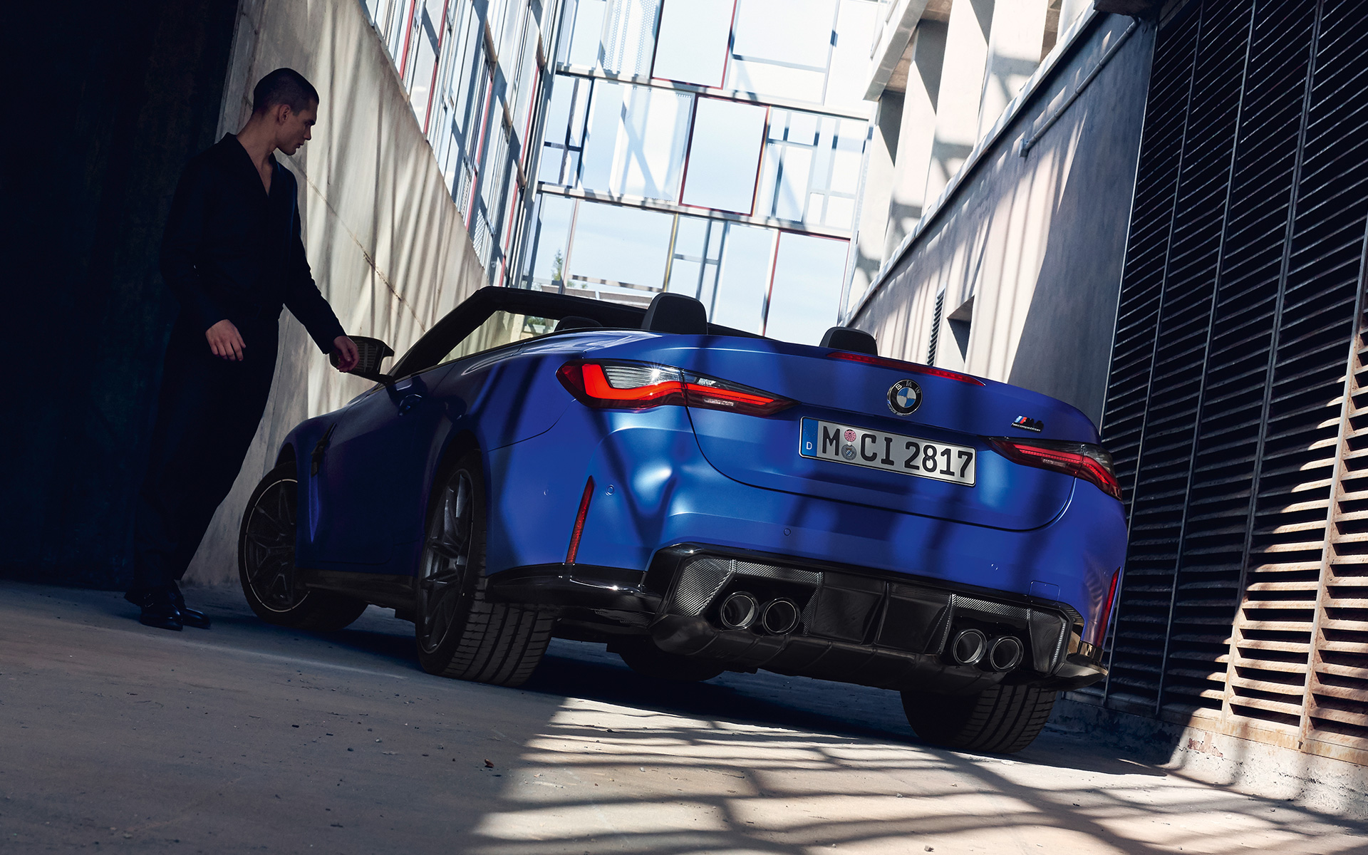 BMW M4 Competition Cabrio con sistema M xDrive G83 2021 BMW Individual Frozen Portimao Blau metalizado, vista de tres cuartos de la zaga con hombre