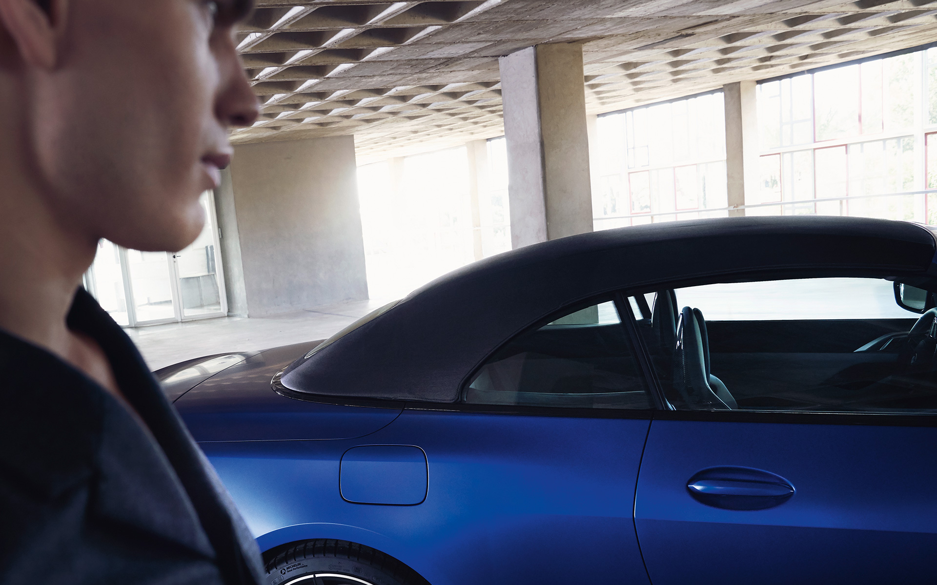 BMW M4 Competition Cabrio con sistema M xDrive G83 2021 BMW Individual Frozen Portimao Blau metalizado, con capota cerrada y hombre en primer plano