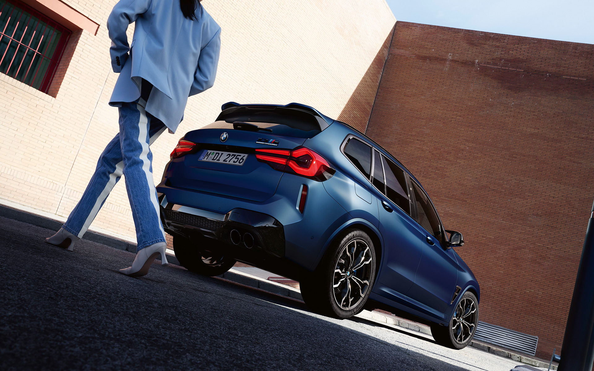 BMW X3 M Competition F97 LCI Renovación 2021 Frozen Marina Bay Blue metalizado, vista de tres cuartos de la zaga con modelo, perspectiva desde ángulo inferior