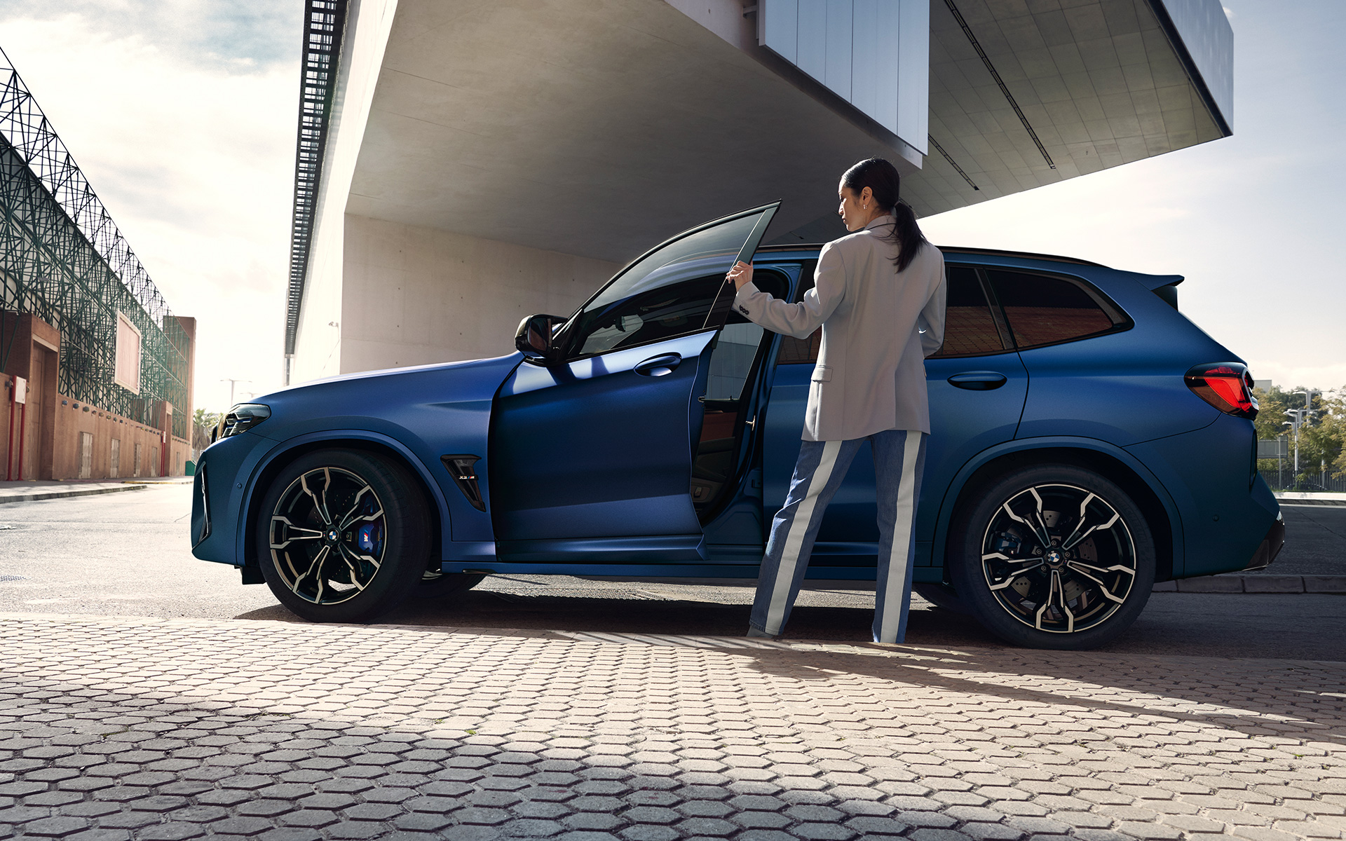 BMW X3 M Competition F97 LCI Renovación 2021 Frozen Marina Bay Blau metalizado, vista lateral con la puerta abierta y modelo femenina