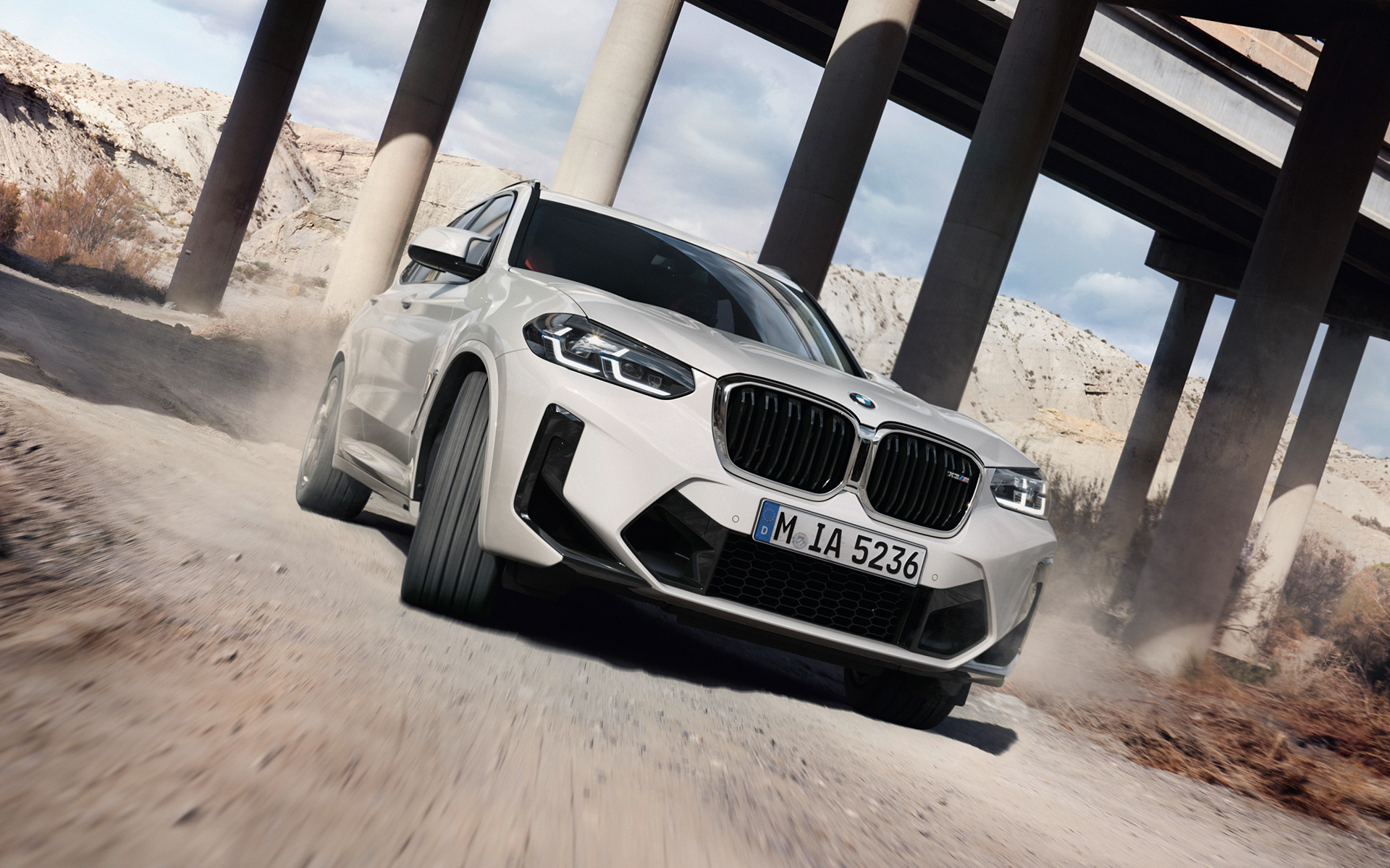 BMW X3 M F97 LCI Renovación 2021 Alpinweiss, vista de tres cuartos del frontal, en marcha trazando una curva