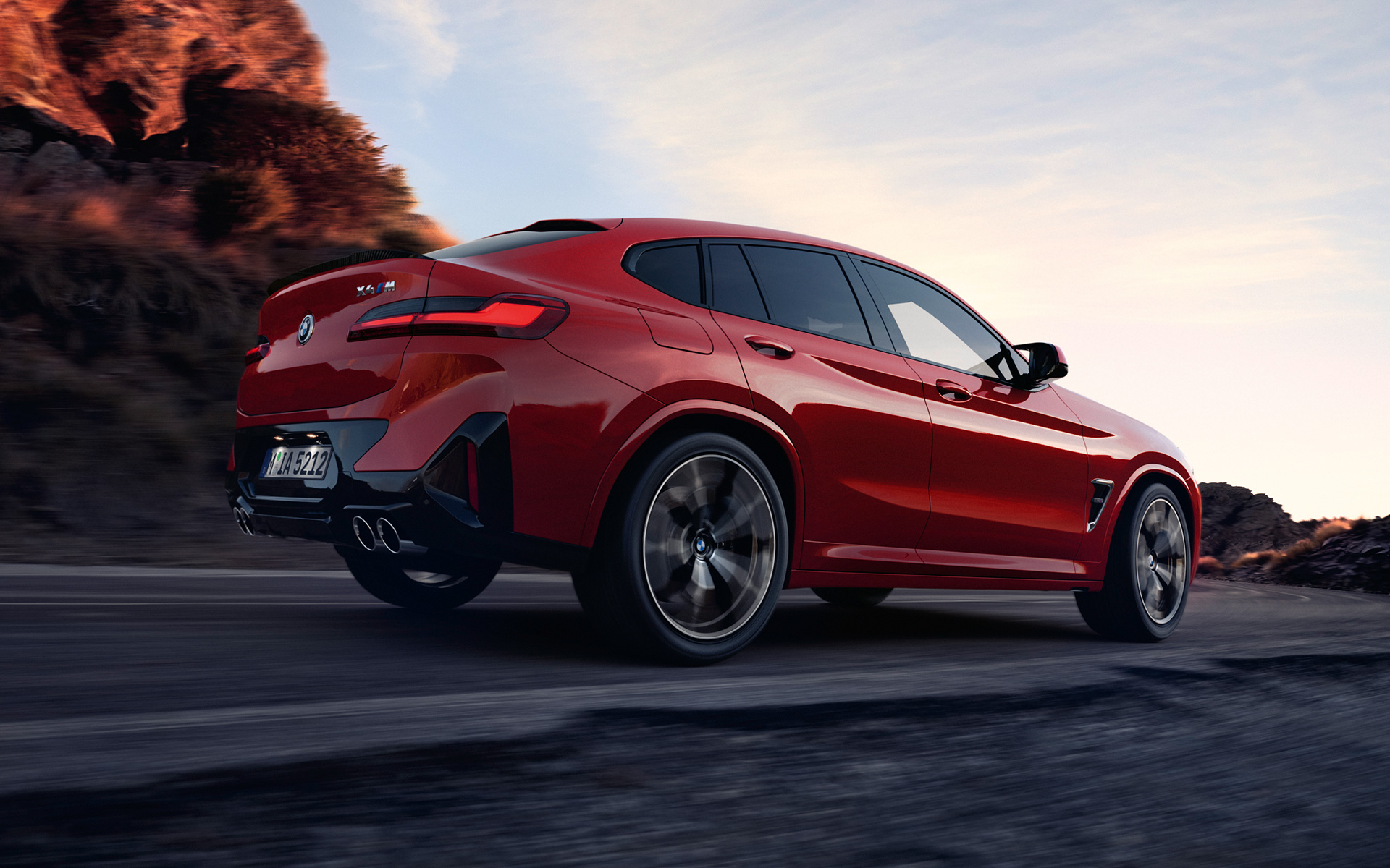 BMW X4 M F98 LCI Renovación 2021 Toronto Rot metalizado Vista de tres cuartos de la zaga circulando por una carretera