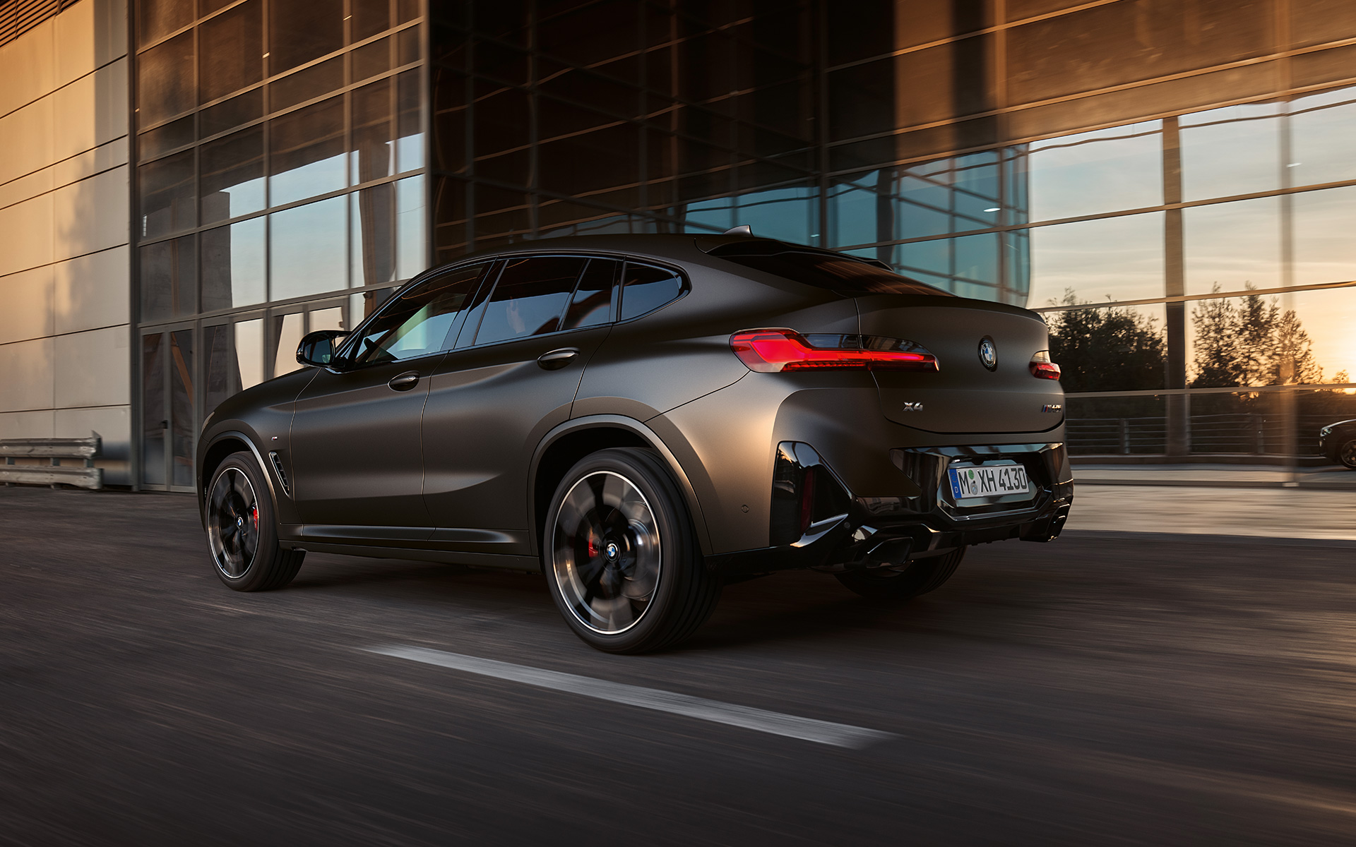 BMW X4 M40i G02 LCI Renovación 2021 Vista de tres cuartos de la zaga delante de fachada de cristal